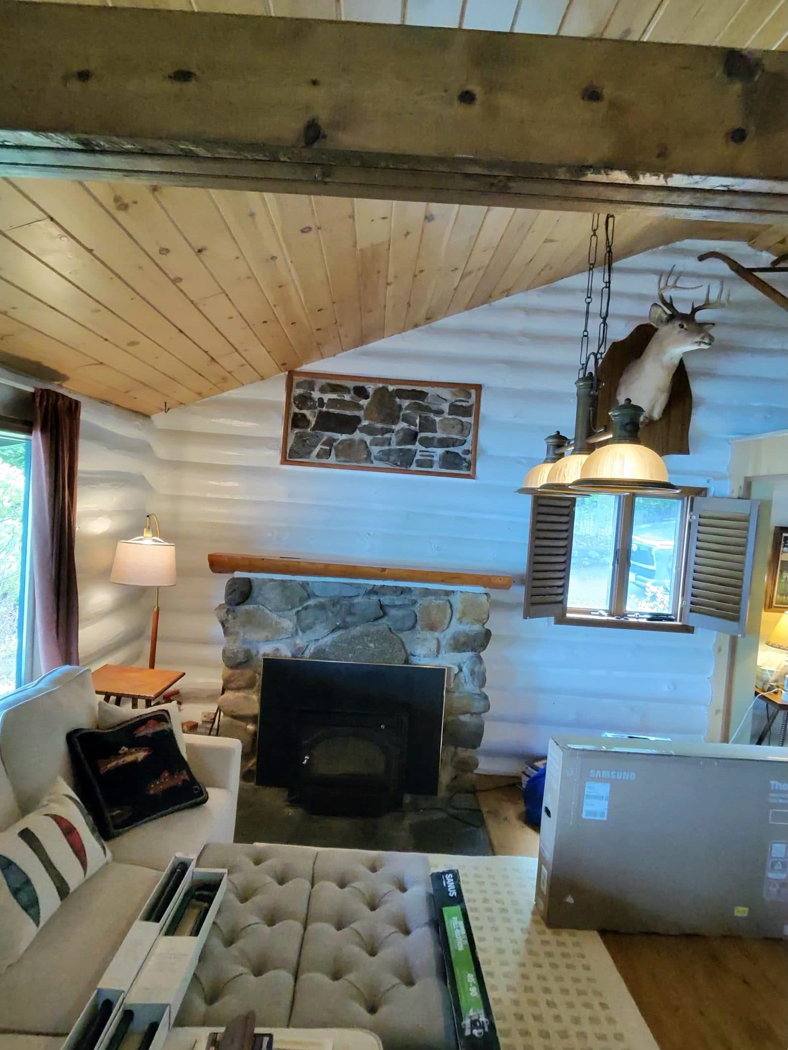 Log cabin great room with a stone fireplace prepped for a TV mount