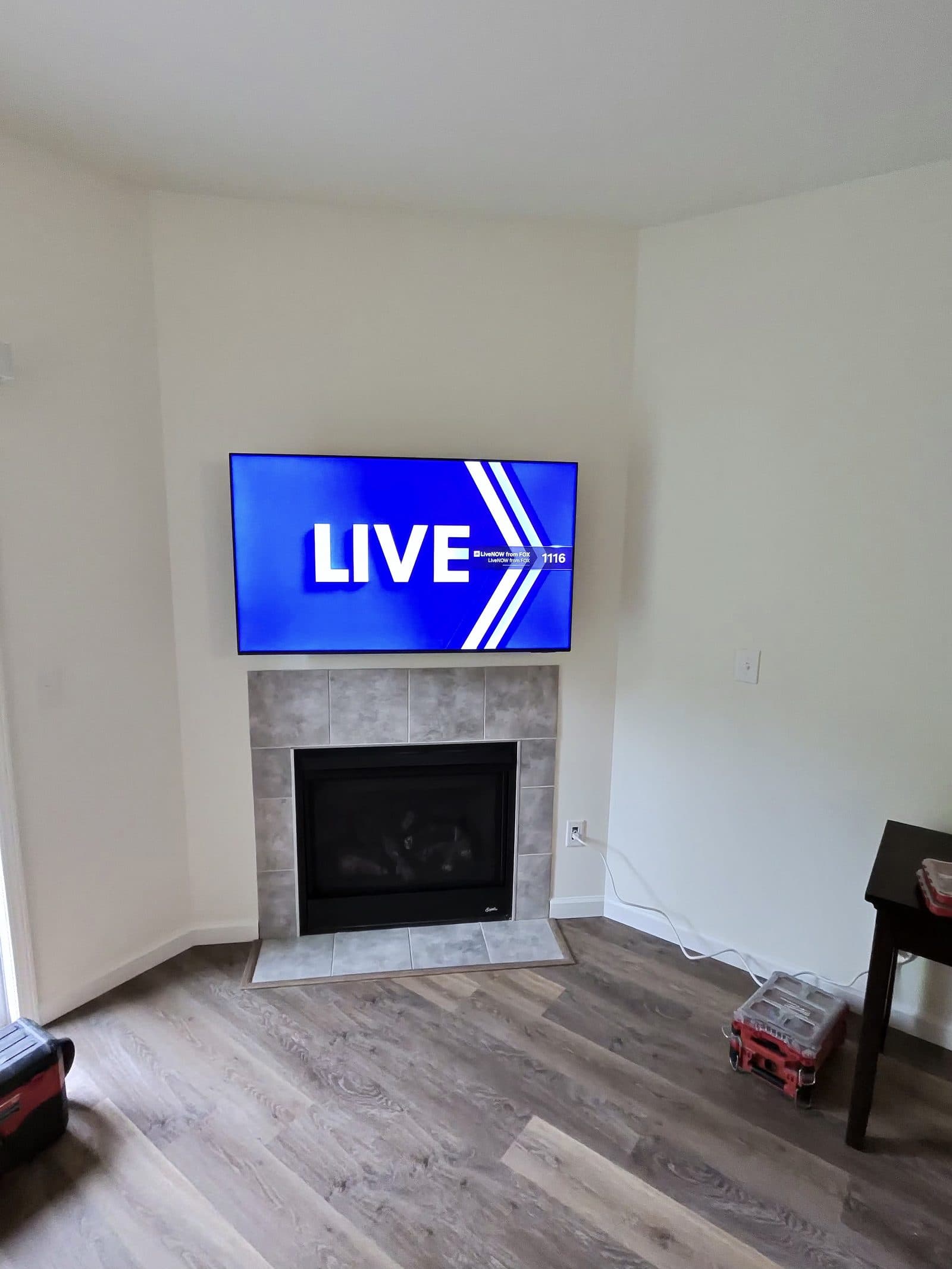 TV corner-mounted above a tiled fireplace in a freshly finished living room