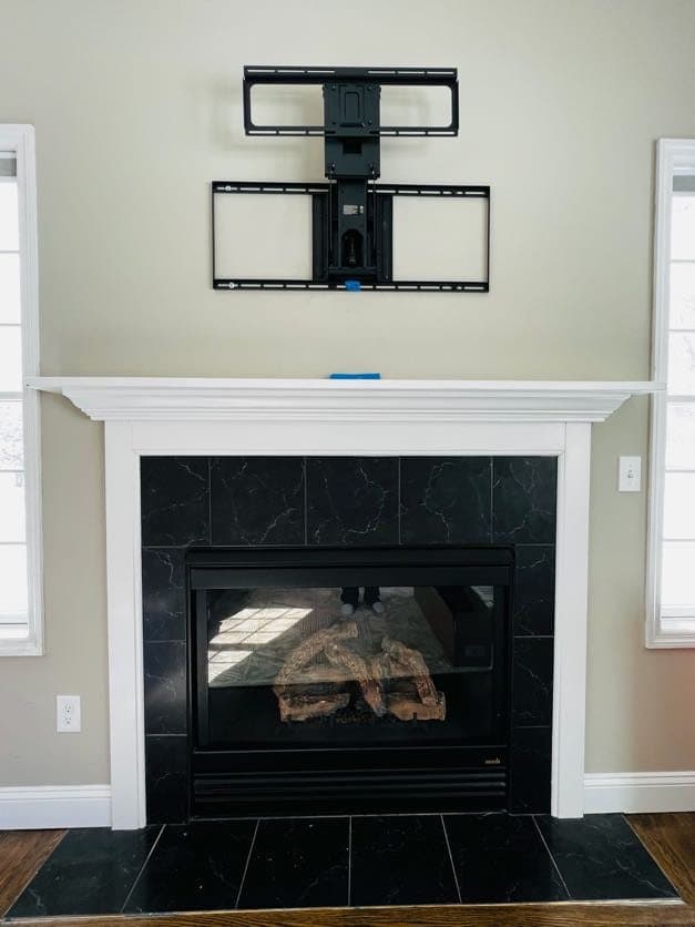 Articulating TV mount over a black marble fireplace