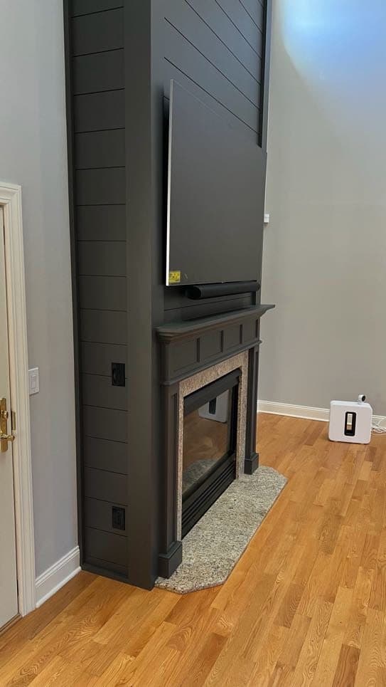 TV on a motorized mount over a dark shiplap fireplace