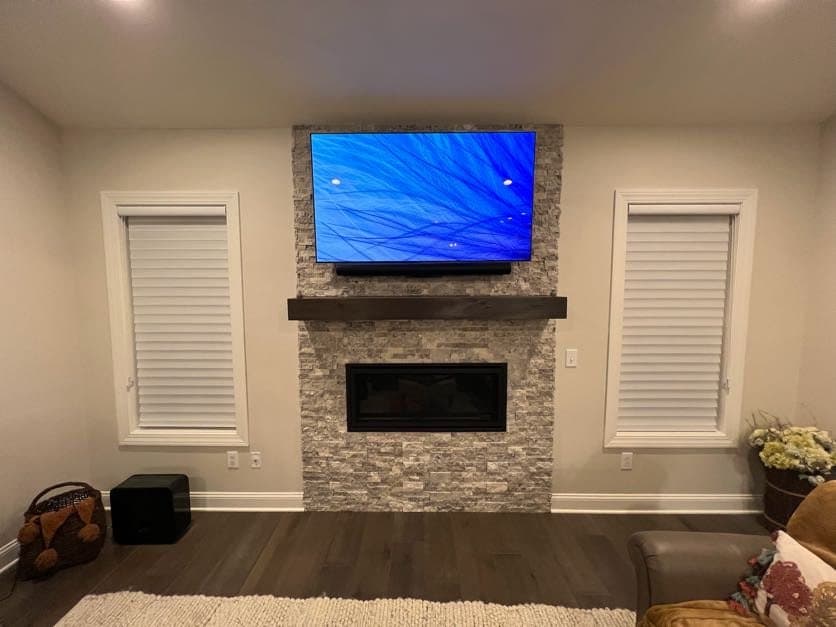 TV mounted over a stone fireplace with soundbar and accent art