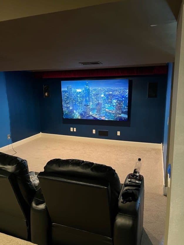 Dedicated home theater room with recliner seating and a city skyline on screen