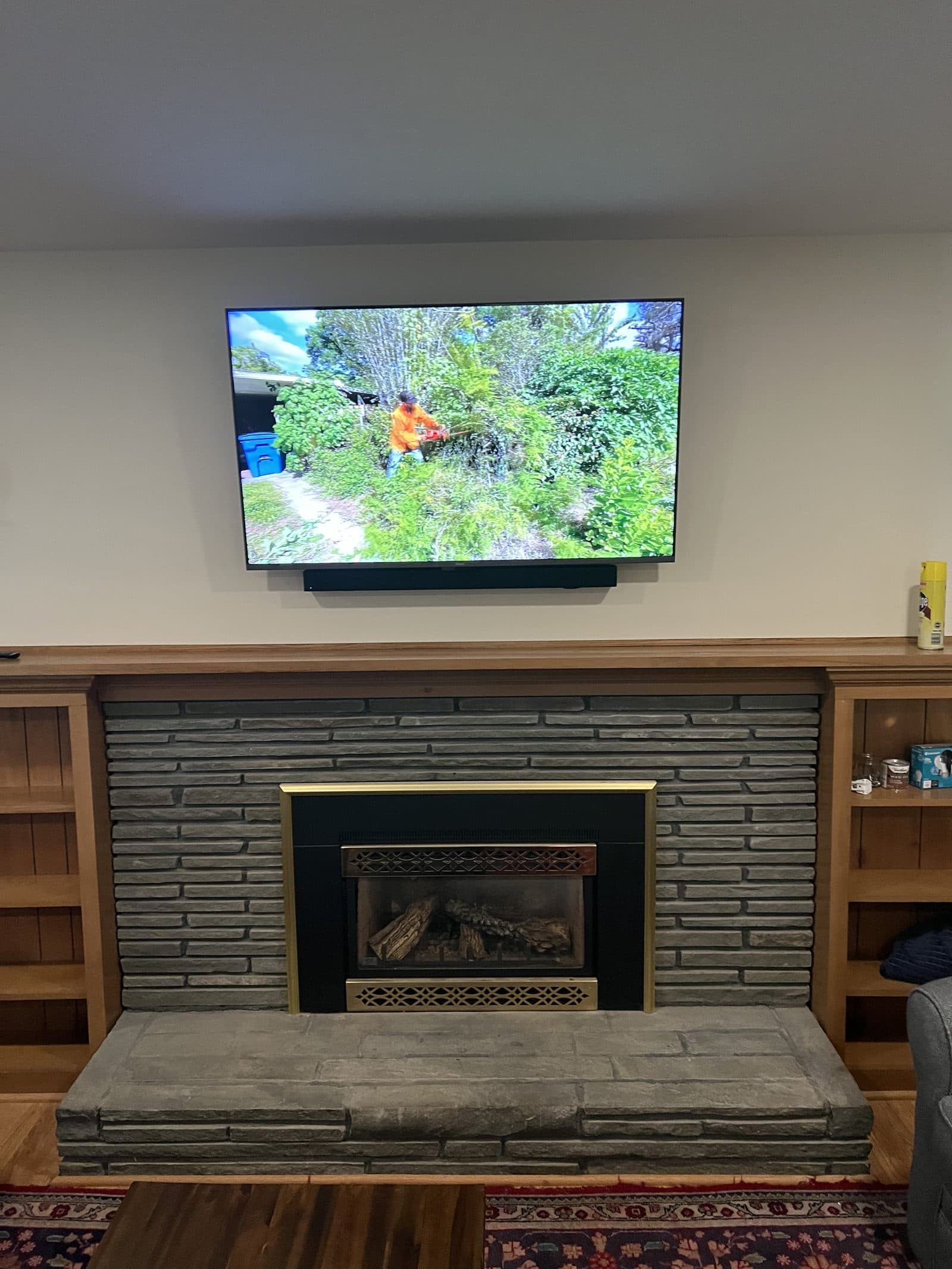 Large TV mounted above a stone fireplace with built-in soundbar