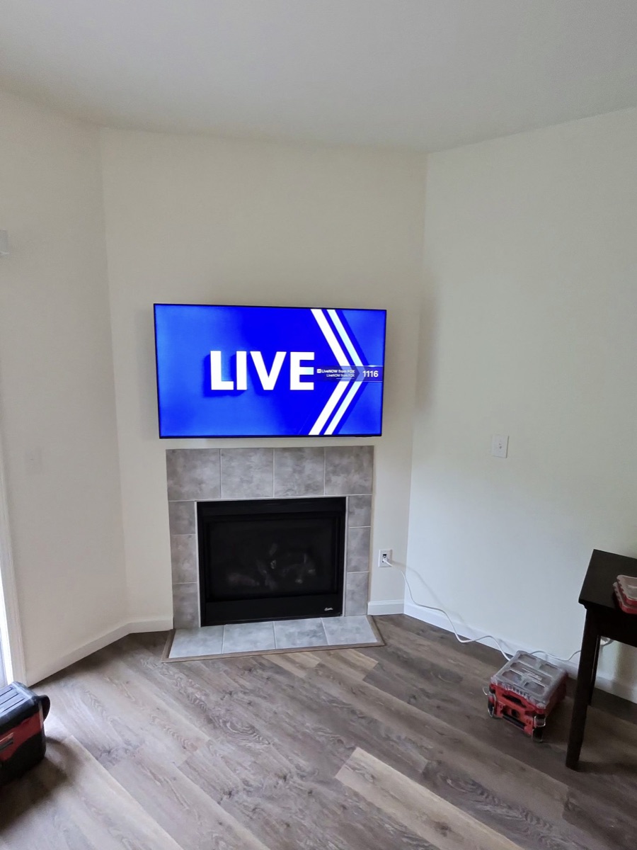 TV corner-mounted above a tiled fireplace in a freshly finished living room