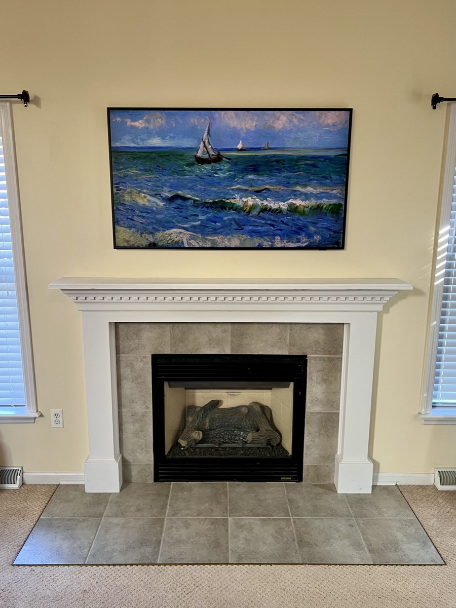 Frame TV displaying a van Gogh seascape above a tiled fireplace