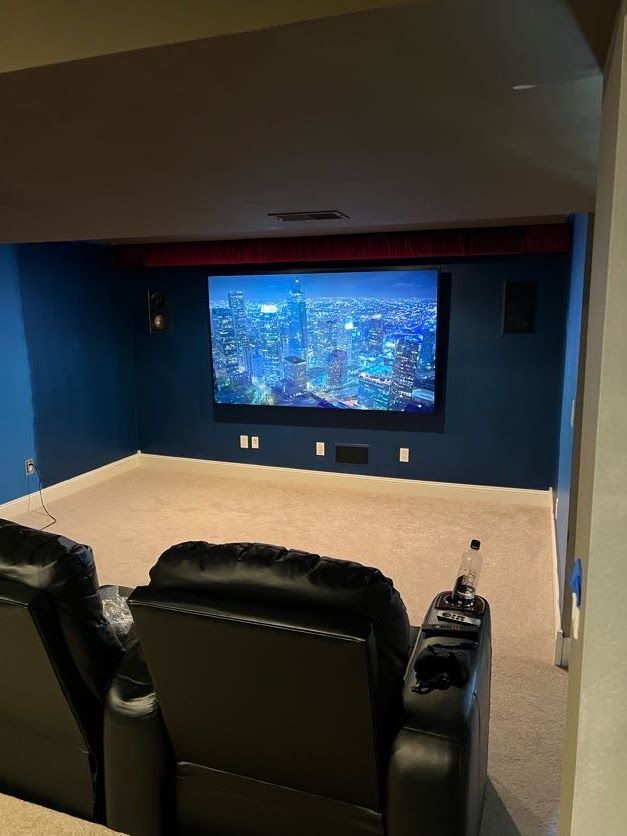 Dedicated home theater room with recliner seating and a city skyline on screen